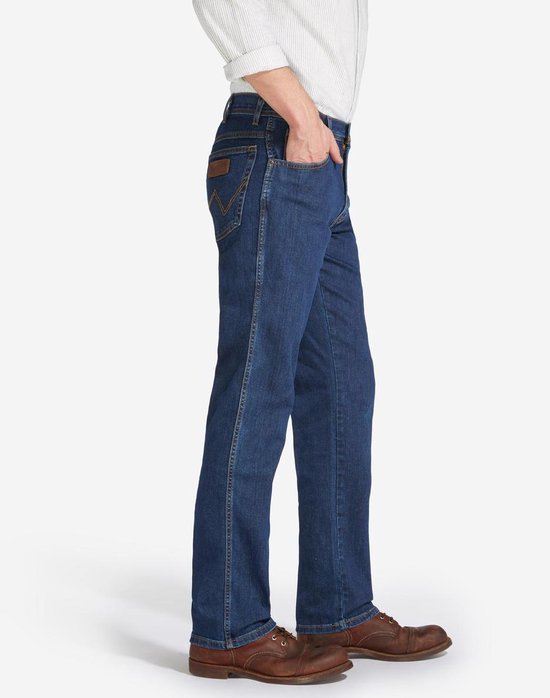 Blauwe Wrangler jeans, regular fit, gedragen met wit gestreept overhemd en bruine schoenen, zij-aanzicht.