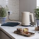 Beige Princess waterkoker met ribbelpatroon op een aanrecht met een glas thee en koekjes.