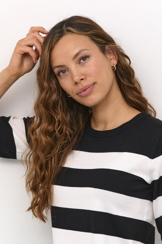Close-up van een model die haar aanraakt, draagt een zwarte trui met brede witte horizontale strepen.