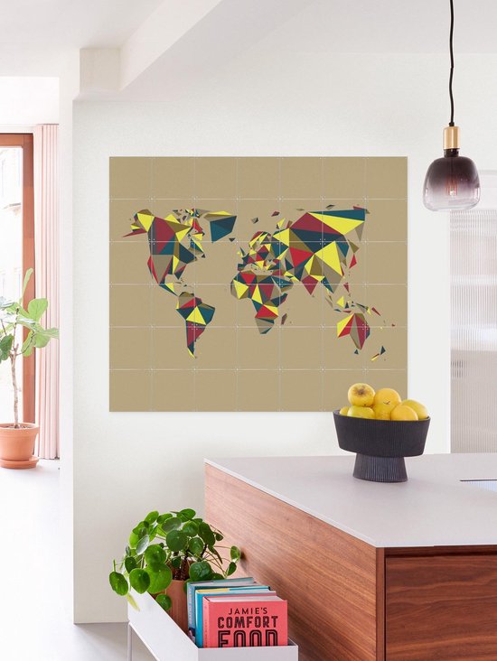 Carte du monde abstraite aux polygones multicolores, accrochée au-dessus d'un îlot de cuisine avec une corbeille de fruits.