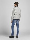 Man van achteren gezien, draagt een grijze jas, zwart shirt en blauwe spijkerbroek.