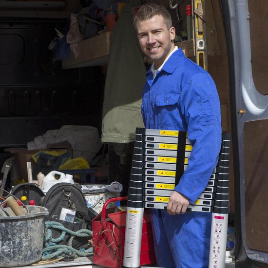 Man in blauw werkpak houdt compacte, ingeschoven ladder bij een werkbus.