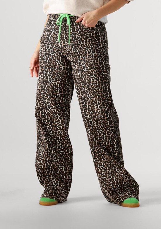 Een model draagt een wijde bruine spijkerbroek met luipaardprint en een groene trekkoord.