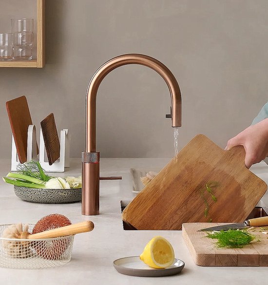 Koperkleurige Quooker kraan in gebruik, met water dat uit de kraan stroomt in een gootsteen.