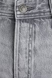 Detail van de knoopsluiting van een lichtgrijze jeans met geverfde textuur.