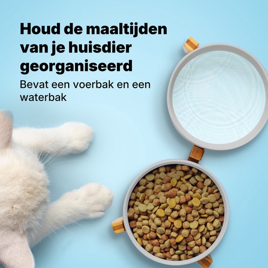 Witte kat kijkt naar grijze keramische dubbele voerbak op bamboe standaard, met een vergrootglas boven de waterbak.