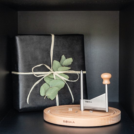 Houten kaasplank met kaas prikker en kaas rasp, naast een cadeau.