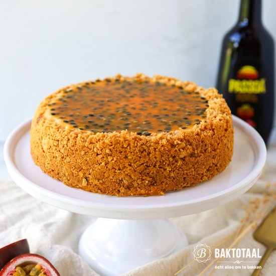 Cheesecake met passievrucht topping en een kruimelbodem, geserveerd op een witte taartschaal.