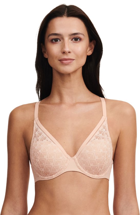 Geposeerde vrouw met lang zwart haar, draagt een beige beha met geometrisch kant.