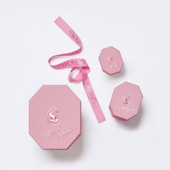 Roze verpakkingen met Ariana Grande en Swarovski logo's, en roze lint.