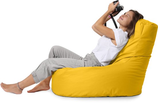 Vrouw met camera zit op een gele zitzak.