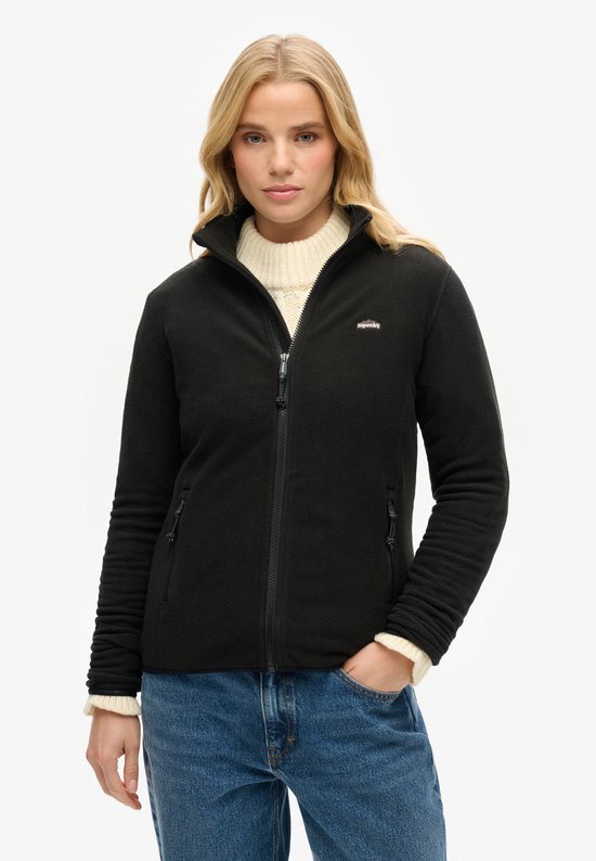 Mannequin portant une veste polaire noire zippée, pull à col roulé en tricot, jean et ceinture.
