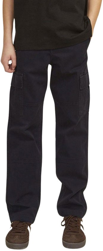 Vooraanzicht van een jongen in donkergrijze cargo broek en bruine sneakers.
