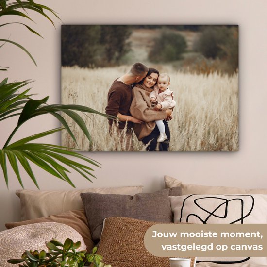 Een gezin met een baby in een veld van droog gras, de man kust de vrouw op haar wang.