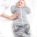 Baby in grijze Love to Dream™ Swaddle Up™ met witte strepen, armen omhoog, met een hand op de buik.