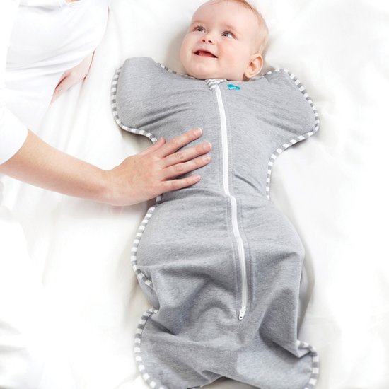 Baby in grijze Love to Dream™ Swaddle Up™ met witte strepen, armen omhoog, met een hand op de buik.