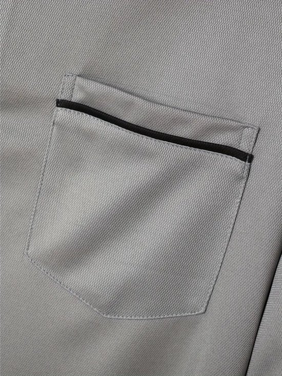 Close-up van borstzakje van grijs poloshirt met zwarte bies.