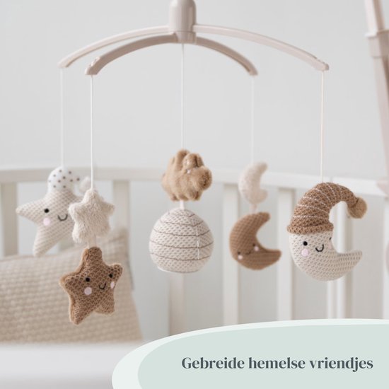 Muziek-mobiel met gebreide sterren, maan en wolkjes boven een ledikant.
