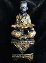 Sfeervol beeld van een kindermonnik met blad 8.5x24x8.5cm  bestaat uit twee kleuren, mat zwart & goud. Daardoor past het zowel in een klassiek als in een modern interieur.De uitstr