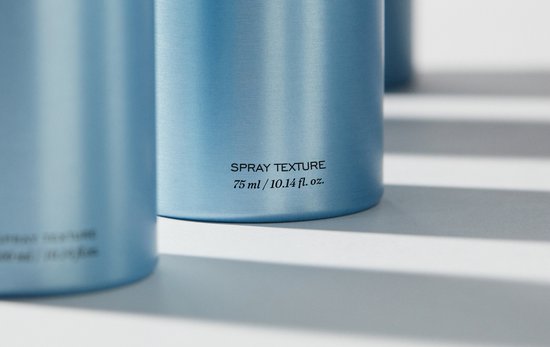 Onderkant van blauwe REF sprayflessen met de tekst 'SPRAY TEXTURE 75 ml / 10.14 fl. oz.'.