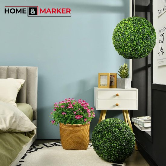 Een slaapkamer met een decoratieve buxusbol aan de muur en een andere op de grond, naast een mand met bloemen.