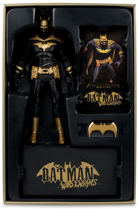 Verpakking met een actiefiguur van Batman, een kaart, een vleermuislogo-accessoire en een sokkel, allemaal met zwarte en gouden kleurenschema's.