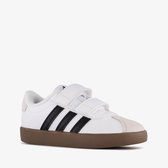 Witte sneaker met klittenbandsluiting, zwarte strepen en bruine zool.