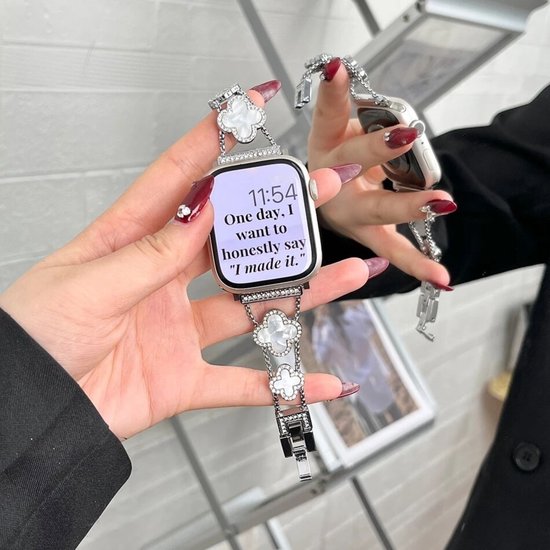 Zilveren bandje met klavervormige parelmoer details en strass steentjes om een Apple Watch.