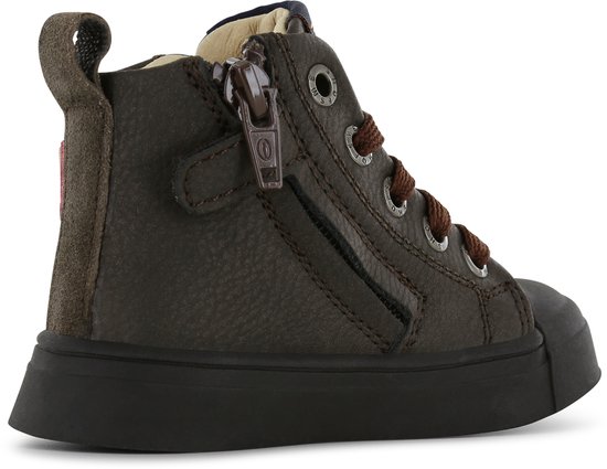 Close-up van de zijkant van een donkerbruine leren hoge sneaker met ritssluiting en veters.