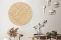 Décoration murale ronde en rotin avec motif tressé, suspendue à un mur blanc au-dessus d'une table en bois.