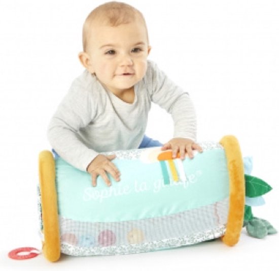 Een baby leunt op de rollende speelrol. De rol is mintgroen met oranje uiteinden en heeft een patroon van sterren en bladeren.