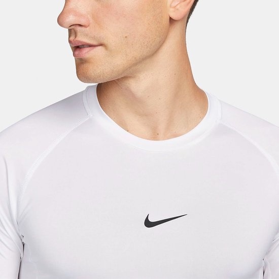 Close-up van een man die een wit Nike Pro longsleeve shirt draagt met een zwart Nike logo op de borst.