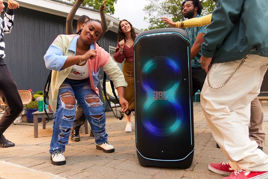 Groep mensen die buiten dansen rond een zwarte JBL PartyBox Ultimate met blauwgroene lichtshow.