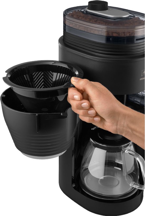 Een hand verwijdert een zwart filterhouder uit een Melitta koffiezetapparaat.