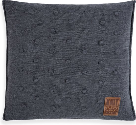 Antracietgrijs sierkussen met nopjesmotief en bruin label.
