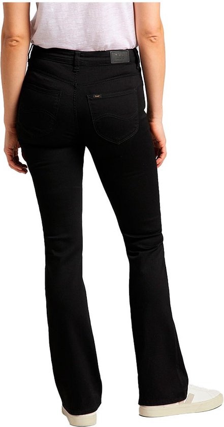 Model van achteren gezien in zwarte flared jeans met witte sneakers en een wit T-shirt.