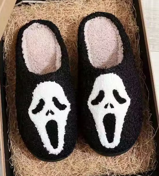 Paar zwarte fuzz-pantoffels met witte 'Scream'-maskers, liggend in een doos.