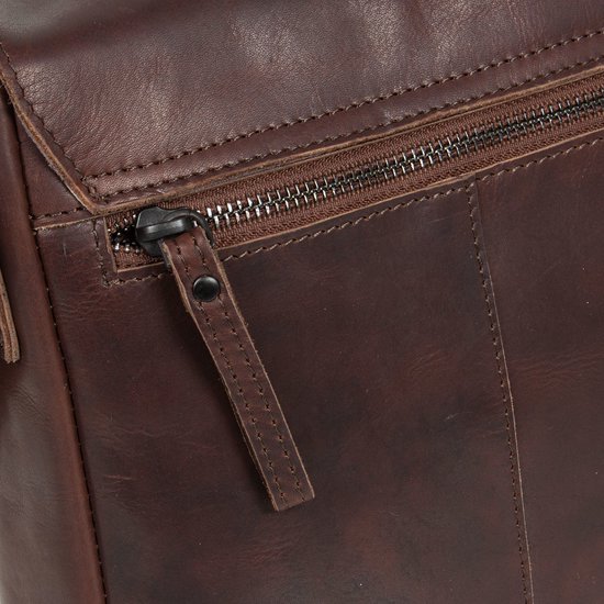 Detail van een donkerbruine leren tas met een rits en leren lipje.