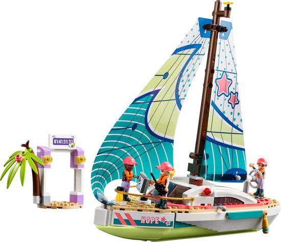LEGO Friends zeilboot met drie poppetjes, met een racepoort en palmboom ernaast.