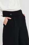 Detail van zwarte wijde broek met knoop- en steekzakdetails aan de voorkant.