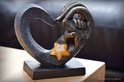 Zwarte hartvormige urn met gouden handen, met een amberkleurige glazen ster.