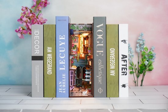 Boekensteun in de vorm van een miniatuur café, tussen gestileerde boeken met titels als 'VOGUE' en 'LECUYE'.