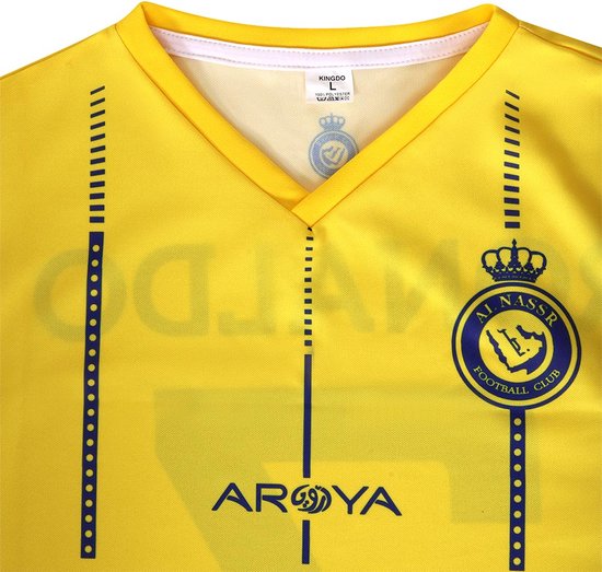 Detail van de kraag van een geel voetbalshirt met het clublogo, maatlabel 'KINGDO L' en verticale blauwe strepen.