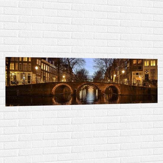 Muursticker - Verlicht Bruggetje over Amsterdamse Grachten - 150x50 cm Foto op Muursticker