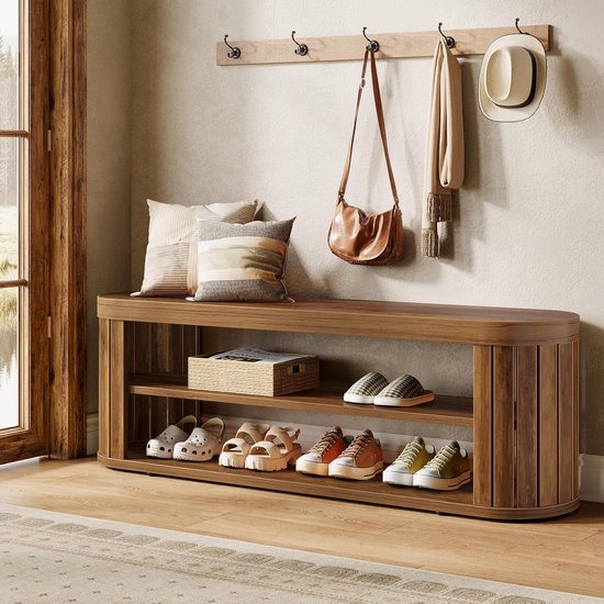 Banc d'entrée en bois aux formes arrondies et lamelles, avec différentes chaussures sur deux étagères ouvertes. Un panier est posé sur l'étagère du haut, des coussins sur le dessus.