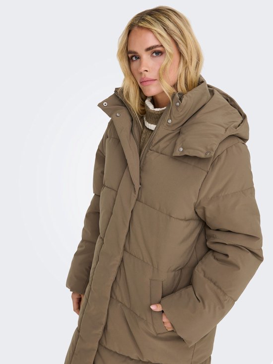 Een vrouw met blond haar draagt een lange, bruine pufferjas met capuchon.