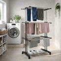 Kledingrek met 3 lagen, donkergrijs, met aan de bovenste laag hangende jeans en broeken, op de middelste laag hangende shirts en handdoeken, en op de onderste laag handdoeken en schoenen.