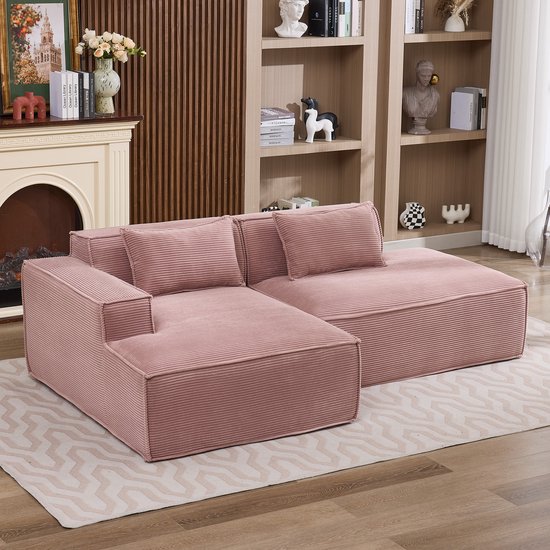 Roze corduroy hoekbank met kussens op een geometrisch vloerkleed.