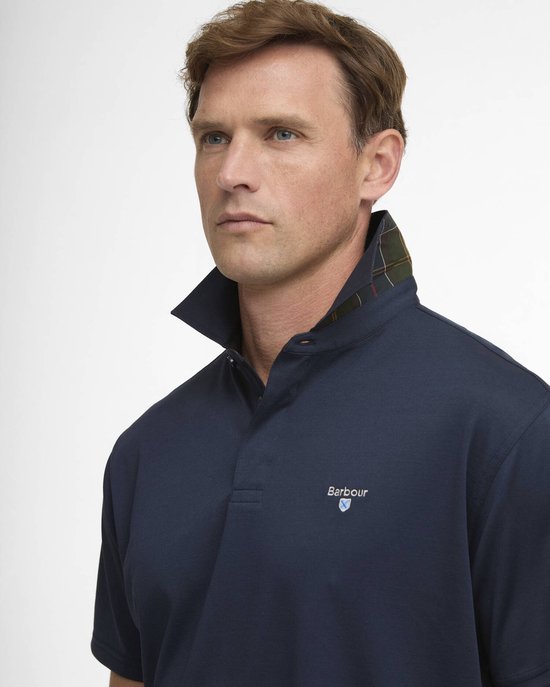 Close-up van een navy polo met korte mouwen, het geborduurde Barbour-logo en de geruite kraag van dichterbij.