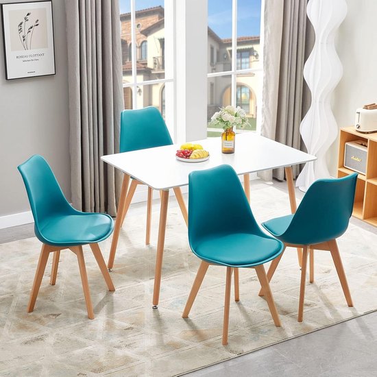 Witte tafel met vier turquoise stoelen in een eetkamer.